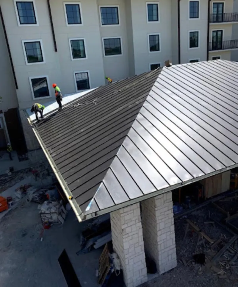 Crew installing standing seam metal roof panels on a commercial project in Vineland